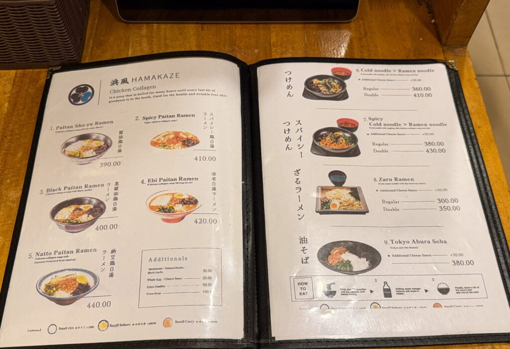 The paitan page of the menu at Hamakaze Ramen open on a wooden table, listing Paitan Shoyu, Spicy Paitan, Black Paitan, Ebi Paitan and Natto Paitan ramen with prices