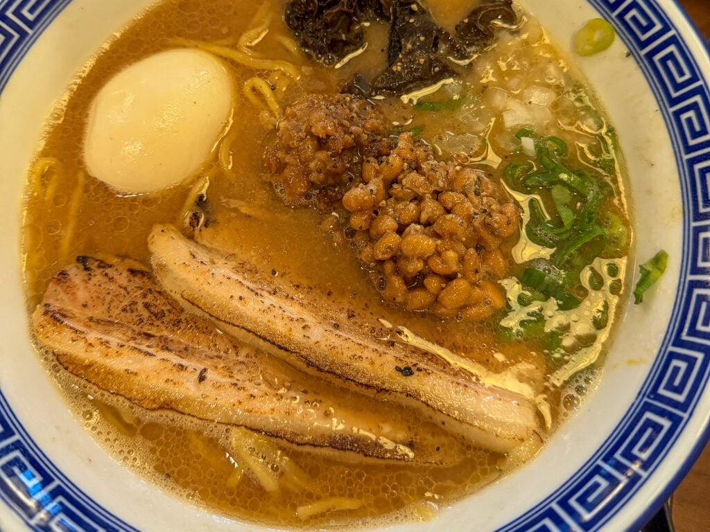 A bowl of chicken paitan ramen at Hamakaze on A.S. Fortuna, thick pale broth with two torched chashu slices, half a soft egg, minced topping, wood ear and spring onion in a blue and white patterned bowl