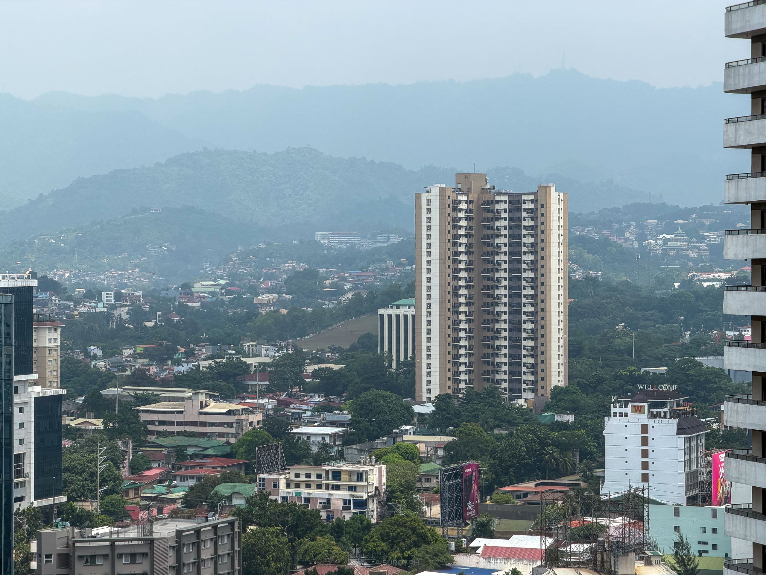 Hills behind Cebu City fading into layers of gray haze above a residential tower.