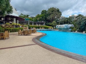 The long curve of the Marco Polo Plaza Cebu pool, terrace tables on the left and a waterfall rock at the far end
