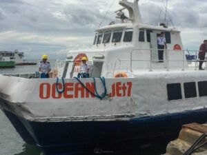 The bow of the fast craft Ocean Jet 7 tied up at a pier, with crew in hard hats and life vests standing on the foredeck