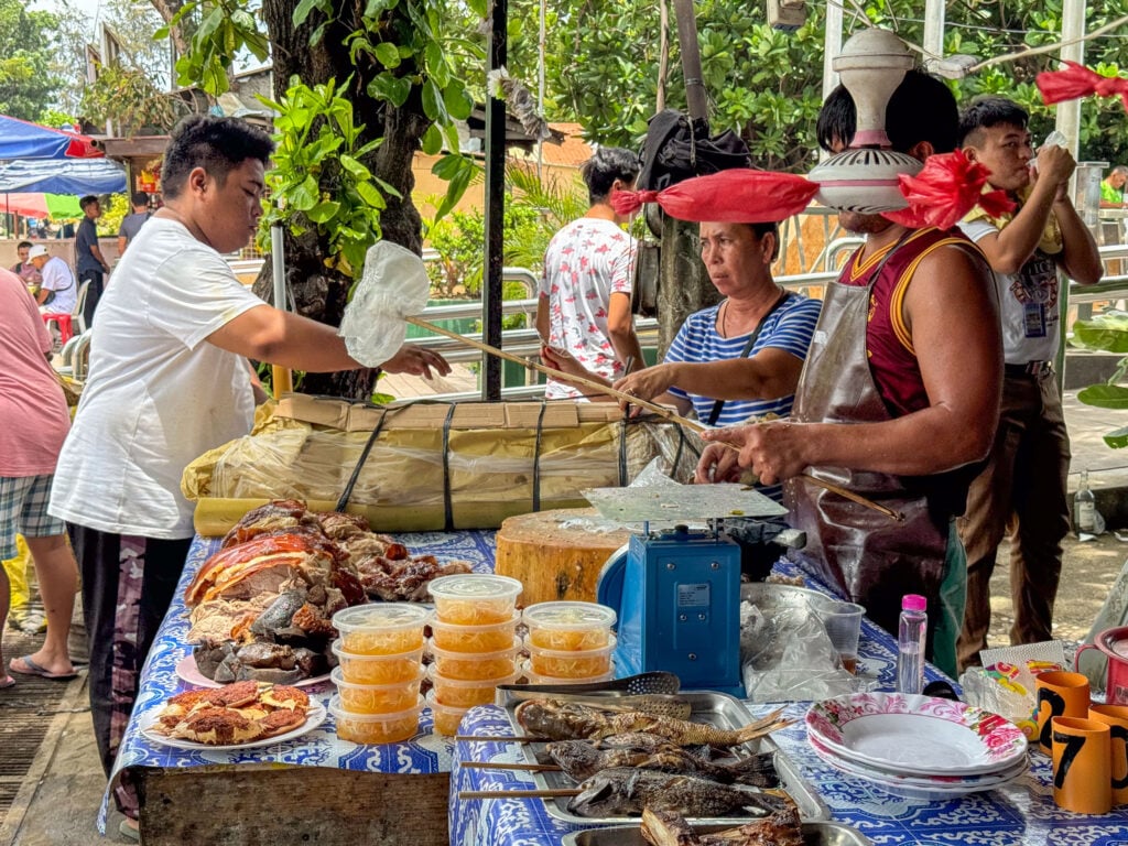 The row of lechon stalls at Talisay Litson Food Park with vendors working behind loaded counters