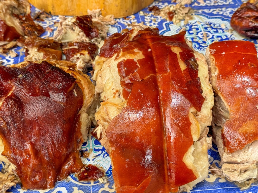 Close up of the crisp skin and fat layer on slabs of Talisay lechon laid on a patterned tablecloth