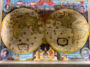 Painted world map mural on the lobby wall of Waterfront Cebu City Hotel, two hemispheres with labelled portraits of Filipino historical figures in the corners