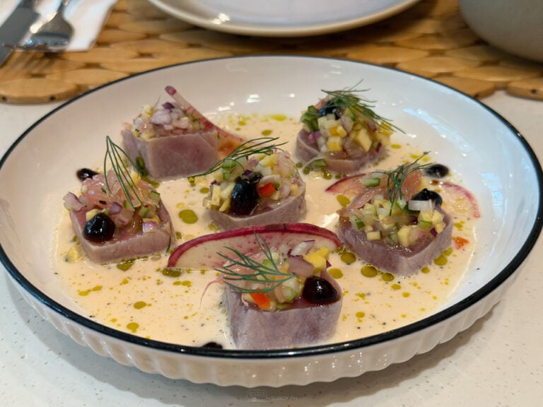 Kinilaw at ATO-AH, cubes of tuna topped with diced fruit and herbs in a pale coconut vinegar dressing in a white bowl
