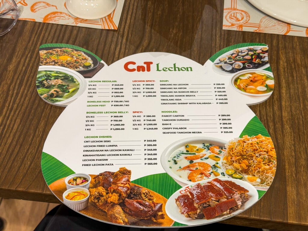 A pig-shaped placemat menu listing lechon by the quarter, half, three quarter and full kilo, with soups, noodles and lechon dishes