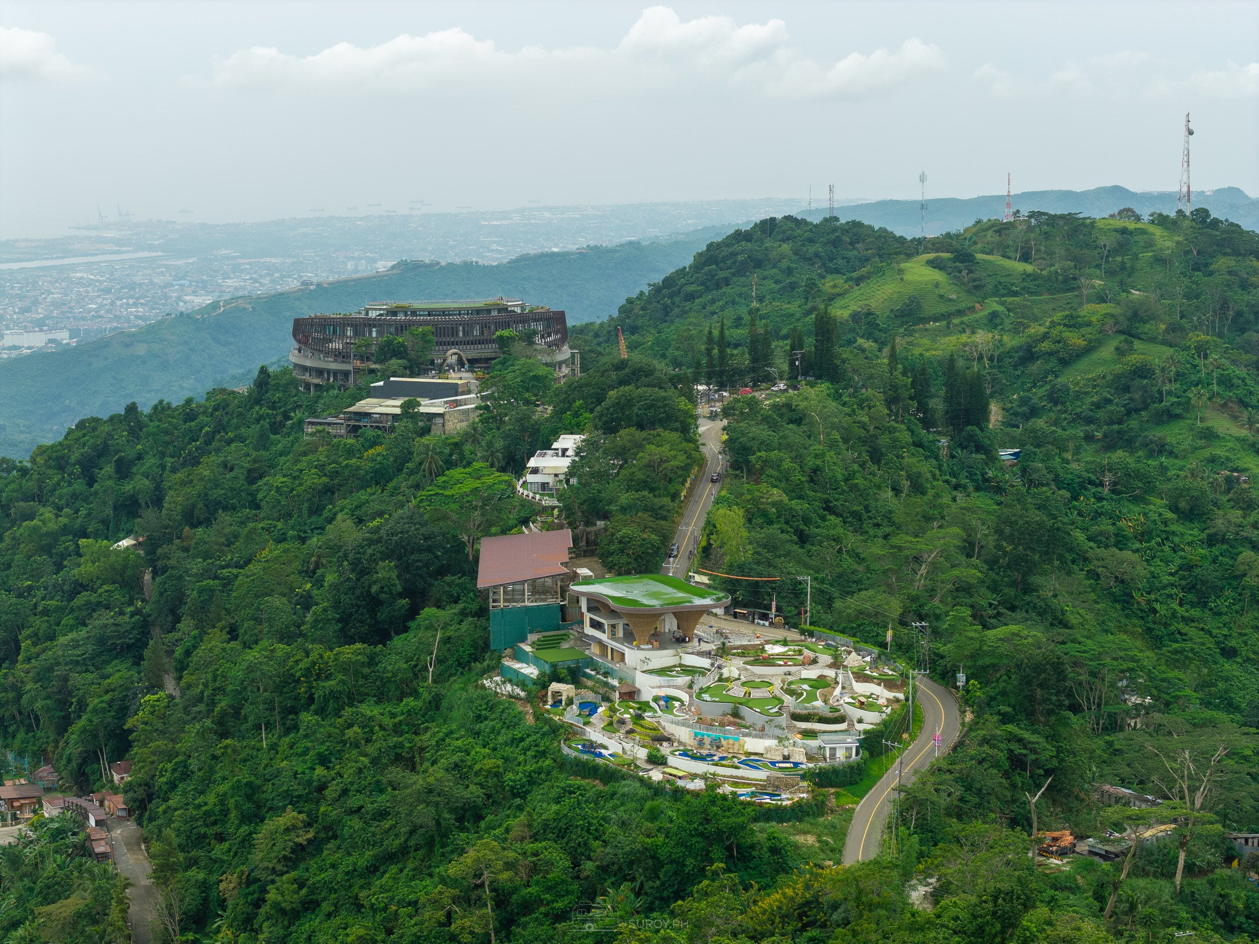 Aerial of the Busay ridge with the mini golf course terraced into the slope and the round Circle building at Tops on the summit above it