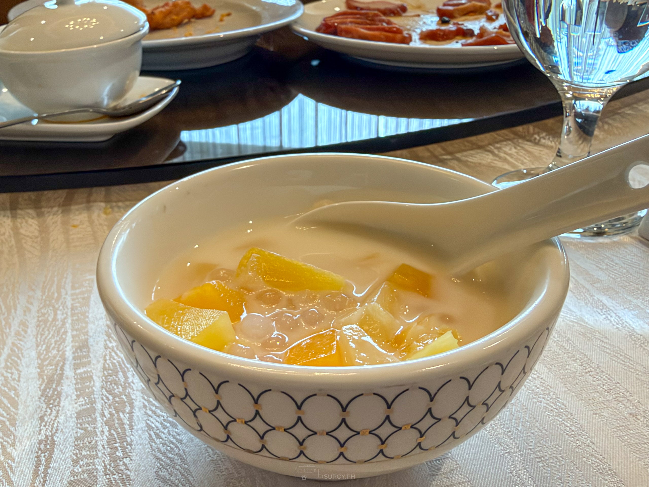 Tapioca fruit mix in a white patterned bowl with a porcelain spoon