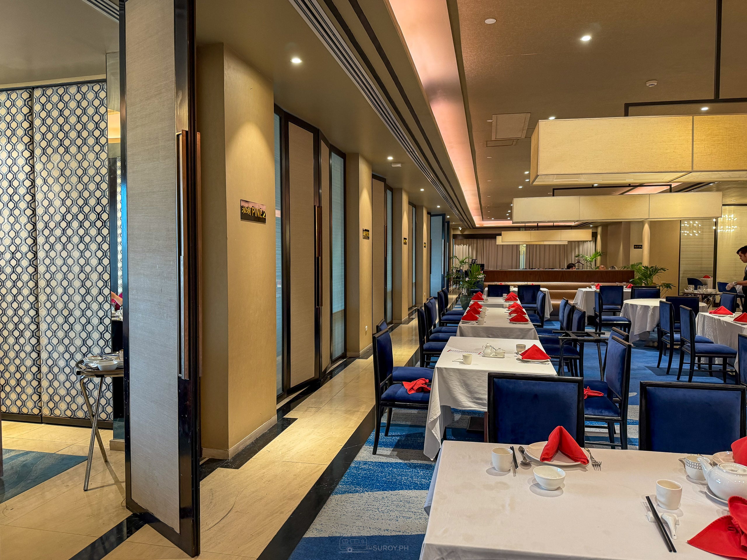The Hai Shin Lou dining room set for lunch, white tablecloths, blue chairs and red napkins
