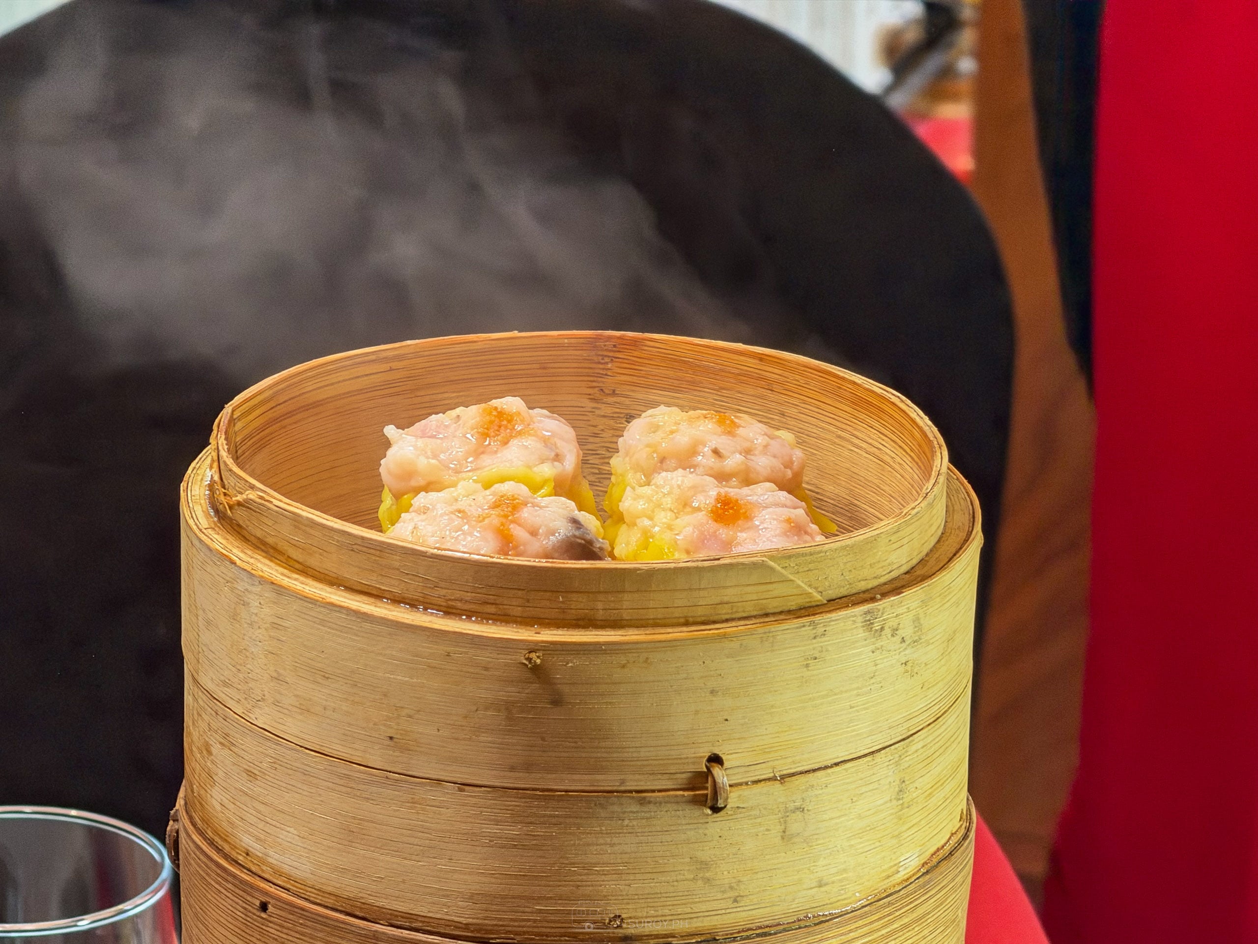 Steam rising off a bamboo basket of ha kaw shrimp dumplings