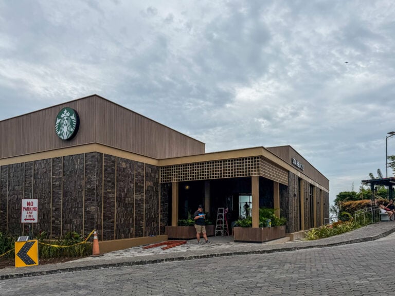Starbucks pavilion at Tops in Busay with dark stone walls, wood slat roofline and the green siren logo, caution tape and cones out front before opening